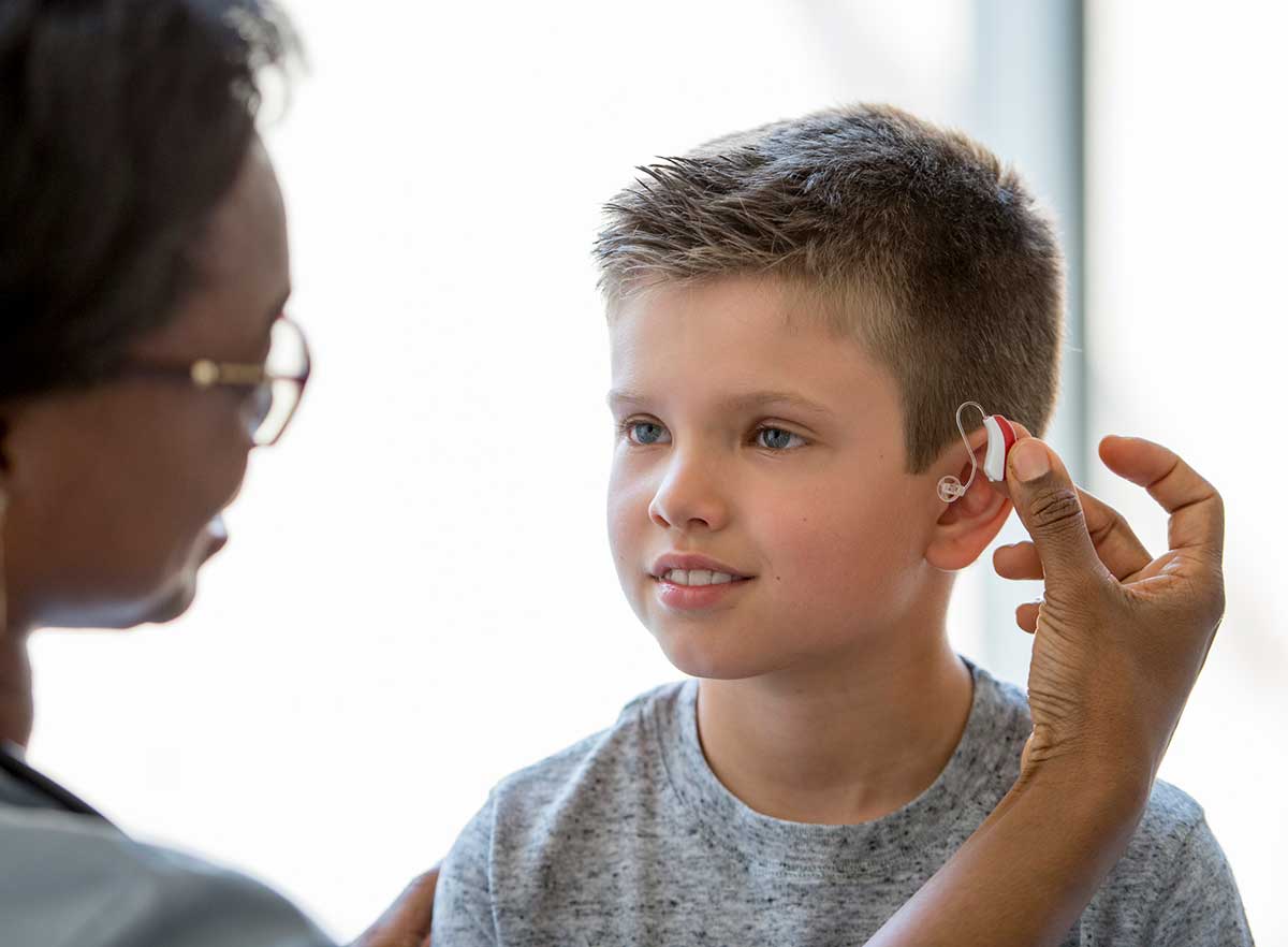 Doctor looking at a boy's hearing aid